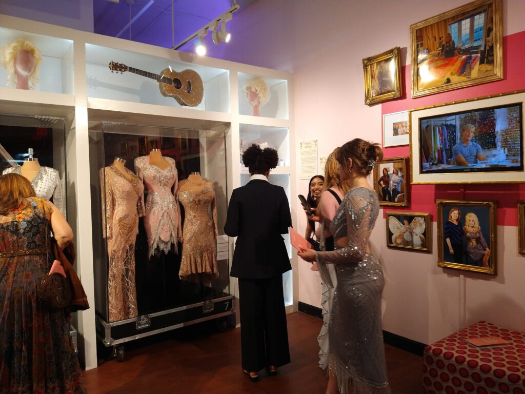 Attendees looks at a display from the “Dolly Parton & The Makers: My Life In Rhinestones” fashion exhibition